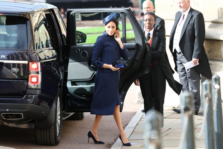 Meghan Markle steps out of an SUV in a navy blue coat.
